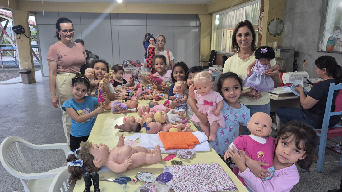 As meninas se encantaram com as novas vestimentas das bonecas do Lar Maria de Nazaré