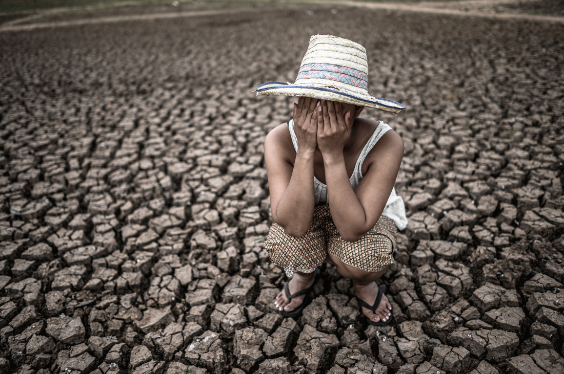  Women sitting on their hands, closed their faces on dry ground in a warming world.